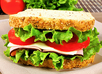 Freshly made sandwich with lettuce and tomato on a whole wheat bun