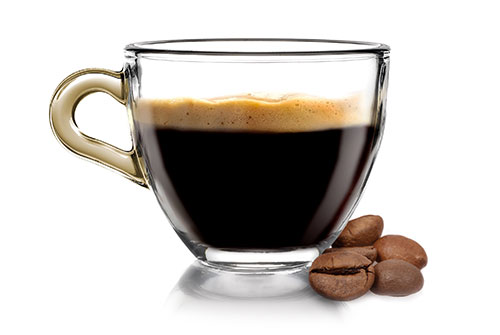 Hot latte in a mug surrounded by coffee beans